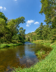 Fototapeta na wymiar river in valley surrounded by forests, blue sky