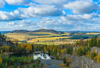 Fototapeta na wymiar flooded quarry with trees around in autumn