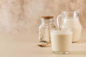 A glass of oat milk, a jug and oat flakes. The concept of alternative lactose-free dairy products. Copy space.