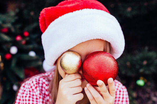 Merry Christmas. Portrait Of Happy Funny Child Girls In Santa Hat With Christmas Tree Toys Near Face. No Face. Happy Holidays. Fairy Magic. Happy Kid Enjoying Holiday. Christmas In July