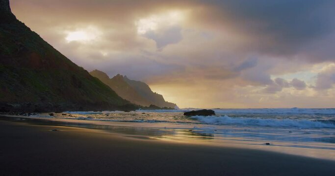Empty black sand beach in Tenerife island during sunset. Relaxation ideal view. Canaries. Atlantic ocean, foamy waves.