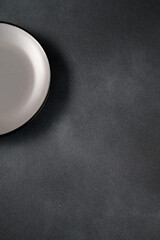 Empty blank gray ceramic round plate or dish on black stone background with copy space.