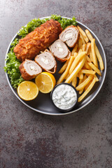 Karageorge Schnitzel Serbian Stuffed Cutlet served with french fries and tartar sauce close-up in a plate on the table. Vertical top view from above