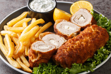 Serbian Breaded Rolled Cutlet Karageorge Schnitzel with french fries and tartar sauce close-up in a plate on the table. Horizontal
