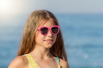 Close-up portrait of a girl in a bathing suit and glasses.