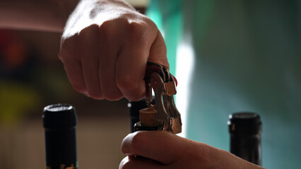 Person hands opening bottle of wine with corkscrew.