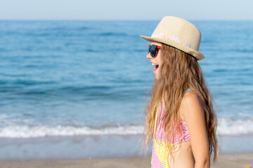 Side view of a girl with an open mouth on the background of the sea.