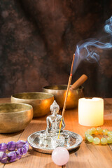Still life with Tibetan singing bowls, minerals, a candle, incense and a Buddha figure.