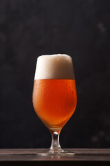 Tulip glass of beer on black background.