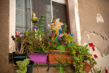 Fototapeta na wymiar Pots decorated with flowers and pinwheels on the facade of an antique house, in the Hystorical Center of the City of Cagliari, Italy