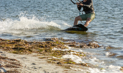 Expert Kitesurfer Planing close to the beach with Pictoresque Sea Watrer Splashes at sunset