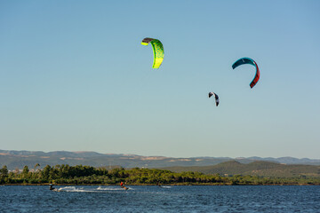 Kitesurfers riding near Punta Trettu, near Cagliari, in Sardinia, Italy, at Golden hour on Blurred Coastline background
