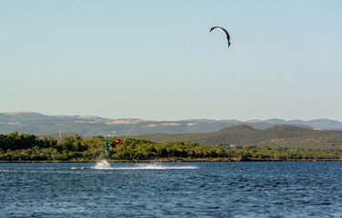 Kitesurfers riding near Punta Trettu, near Cagliari, in Sardinia, Italy, at Golden hour on Blurred...