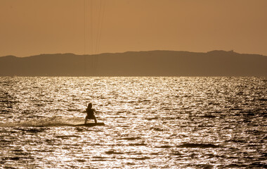 Fototapeta premium Expert Kitesurfer Planing with Sea Watrer Splashes during Golden Hour in backlight on Blurred Background