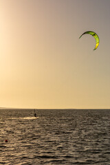 Expert Kitesurfer Planing with  Sea Watrer Splashes during Golden Hour in backlight