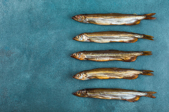 A few smoked capelin on a blue background.
