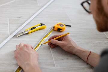 Man measuring decorative plastic corner. Repairing at home.