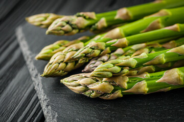 raw green asparagus on a black wooden rustic background