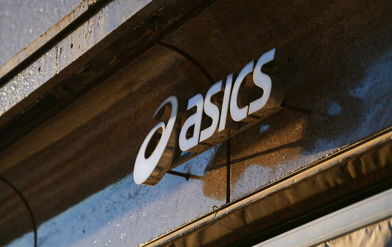 The logo sign of an Asics brand sports equipment store. Spain, 2022