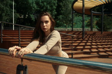 Young happy woman in sportswear warming up on the sports ground before training morning gymnastics