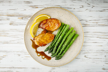 boiled green asparagus and grilled chicken on a white wooden rustic background