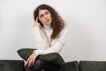 Fototapeta na wymiar A young woman sitting on her dark green sofa with pillow in hands
