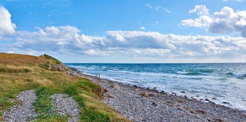 Coast of Kattegat - Helgenaes, Denmark. Ocean waves washing onto empty beach shore stones. Calm peaceful paradise of summer seascape and sky for relaxing fun holiday abroad or travel vacation