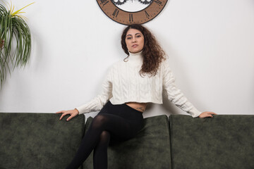 A smiling woman sitting on sofa and looking at camera