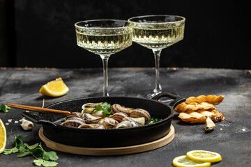 Fried snails Escargots de Bourgogne with herbs, butter, garlic on metal plate with forks, wine glass. gourmet food. Restaurant menu, dieting, cookbook recipe