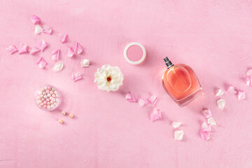 Beauty and cosmetic concept. A bottle of perfume and makeup, overhead flat lay shot on a pink...