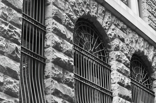 Rock faced stone building with arched windows and bars. Facade a former bank building, 354 George Street Sydney. Black and white image