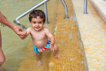 Fototapeta premium A baby in the pool enjoying the summer with his mother