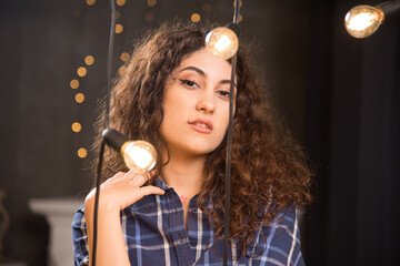 Portrait of a young model in plaid shirt posing near lamps