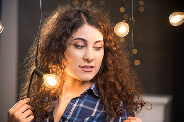 Portrait of a young model in plaid shirt posing near lamps