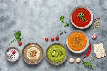 Set of colored vegetable soups. Gray concrete grunge background. Top view.