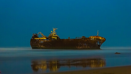 Old boat stuck in the sand of a beach by night
