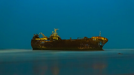 Old boat stuck in the sand of a beach by night