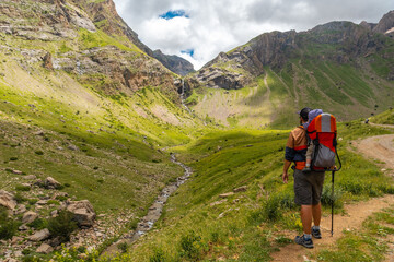 A young man with his son in his backpack, Salto de Tendenera Waterfall in the Ripera Valley, Pyrenees
