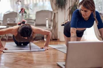 Pretty women working out at home. Adult ladies with beautiful shaped bodies exercising in the...