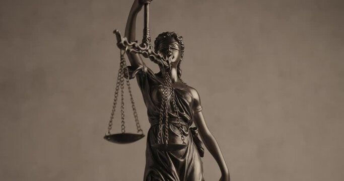 concept of law represented by blindfolded silhouette, bronze law statue spinning and holding a balance balance signifying impartiality and two broad sources of law
