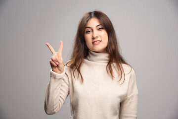 Beautiful woman wearing casual sweater showing and pointing up with fingers number two while smiling