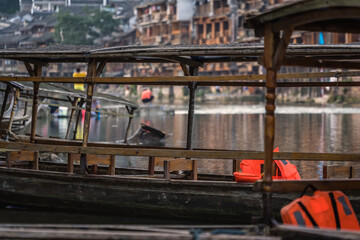 Old wooden boats moored on Tuo river shore in Fenghuang