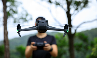 People remote control a flying drone in summer forest