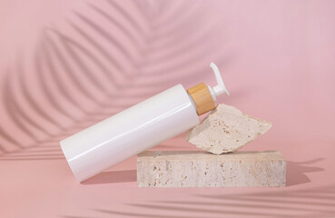 White one pump bottle lies on stone on light pink, palm leaf shadow behind, close up, Mockup