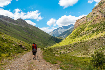 Fototapeta na wymiar A young man in the mountains walking alone in the Ripera valley in summer, Pyrenees