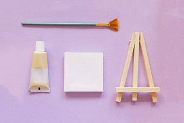 Flatley. Easel, canvas, brush, tube of paint on a lavender background.