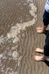 Kids feet in water on the beach - obrazy, fototapety, plakaty