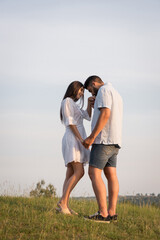 full length of man kissing hand of woman while standing face to face in field.