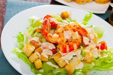 Tasty Caesar salad with shrimps, lettuce, sauce and cheese