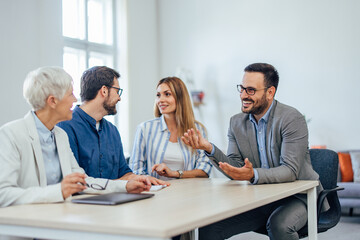 Two females and two males have a meeting at the office, working together on the new project.